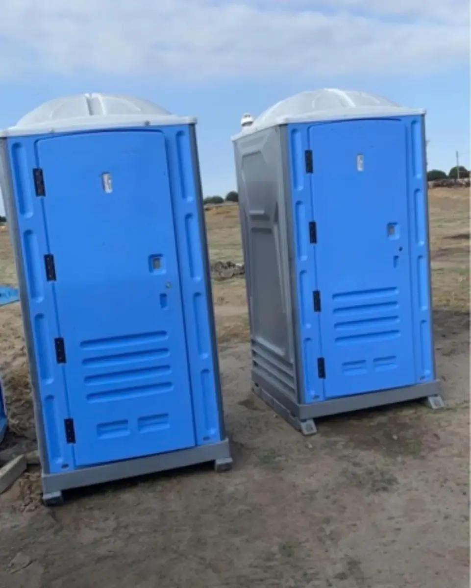 Two standard porta potties on a dirt lot ready for a jobsite